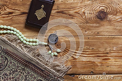 Traditional muslim prayer set bundle. Praying carpet, rosary beads, little version of the Holy Quran and qibla compass on wooden Stock Photo