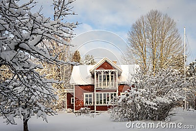 Traditional old big red wooden house in winter countryside. Beautiful cottage or villa with big windows, glazed terrace and balcon Stock Photo