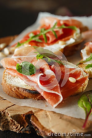 Traditional parma cured ham antipasto. Bruschetta set with Parma Ham and Parmesan Cheese. Small sandwiches with prosciutto, Stock Photo