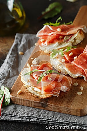 Traditional parma cured ham antipasto. Bruschetta set with Parma Ham and Parmesan Cheese. Small sandwiches with prosciutto, Stock Photo