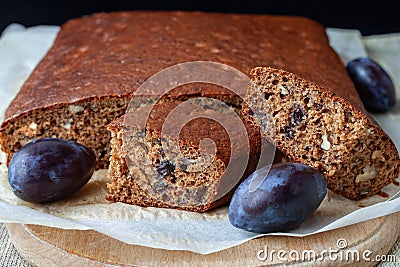 Traditional plum cake with nuts and cut into pieces on an wooden board close-up, selective focus Stock Photo