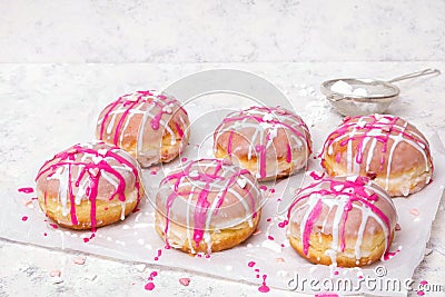 Traditional Polish donuts with pink frosting and heart sprinkles on light background. Stock Photo