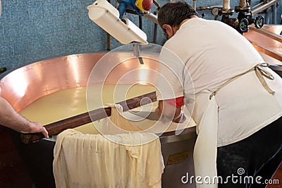 Process of making wheels of parmigiano-reggiano parmesan cheese on small cheese farm in Parma, Italy, copper-lined vats with curd Editorial Stock Photo