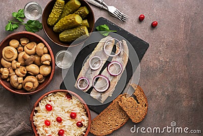 Traditional Russian snacks and vodka, sauerkraut with cranberries, herring, pickled cucumbers, pickled mushrooms and rye bread on Stock Photo