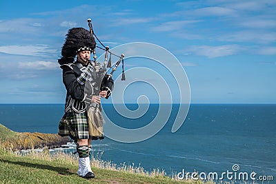 Traditional scottish bagpiper in full dress code at the ocean Stock Photo