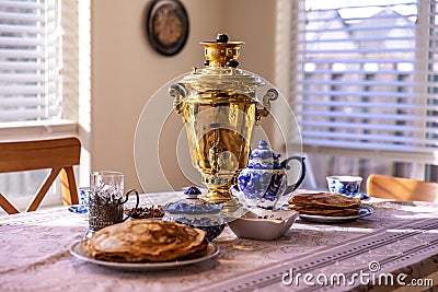 Traditional setup for Russian tea ceremony with samovar, bliny pancakes, teapot, sugar bowl and cups Stock Photo