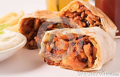 Traditional shawarma wrap with chicken and vegetables ,French fries ,cocktail and garlic paste in a white plate. Stock Photo