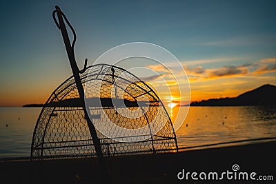 Traditional small net for catching crabs or fish against a beautiful sunset on the sea Stock Photo