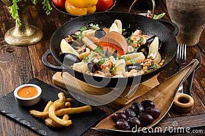 Traditional Spanish dish Paella with seafood: shrimps, squids, mussels, wine, lemon and rice in a black cauldron Stock Photo