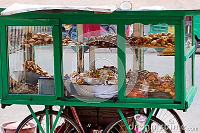 Traditional street food of Sri Lanka - chickpea with coconut, small fried fish, vegetable patties, donuts on a mobile cart. Stock Photo