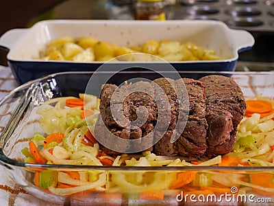 A traditional Sunday Roast meal of a topside roast beef joint and potatoes with herbs and olive oil Stock Photo