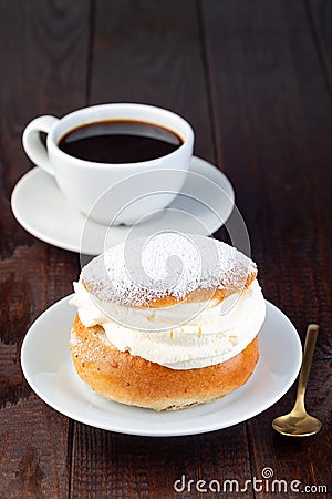 Traditional Swedish dessert Semla or Shrove bun, with almond paste and whipped cream filling, served with cup of coffee, vertical Stock Photo