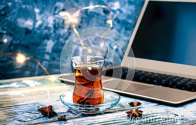 Traditional tea tulip glass armudu on the wooden background and a laptop behind. Stock Photo