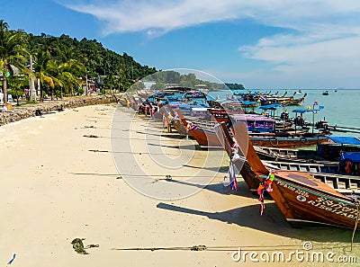 Traditional Thai fishing wooden boats wrapped with colored ribbons. At sand coast of tropical island Editorial Stock Photo