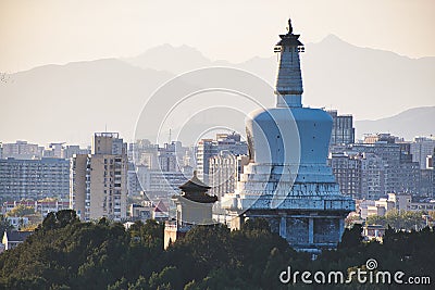 Traditional Tibetan Buddhism white pagoda and traditional Chinese architecture in the sunset, with mountains in the background, th Editorial Stock Photo