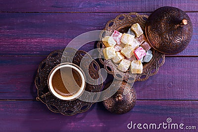 Traditional turkish coffee and turkish delight on dark violet wooden background. Flat lay Stock Photo