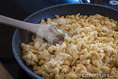 traditional tyrolean house dish kaesspatzn in a pan with a wooden spatula Stock Photo