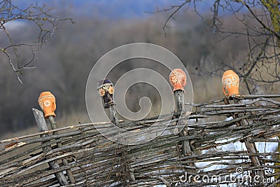 Traditional Ukrainian handmade clay jugs on a wooden fence Stock Photo