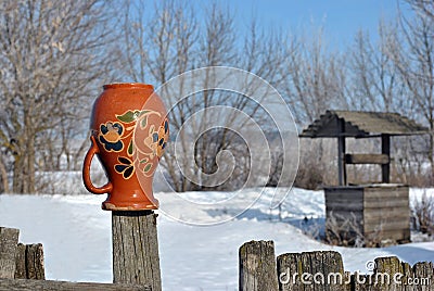 Traditional Ukrainian rural landscape with a wooden well and fence with hanging pitcher on it with Petrykivka folk painting Stock Photo