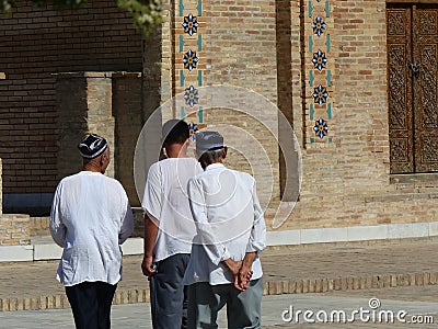 Traditional Uzbek men walking in front of a mosque to Samarkand in Uzbekistan. Editorial Stock Photo