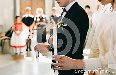 Traditional wedding ceremony at church. Groom and bride are holding candles in their hands. Happy wedding couple on their Editorial Stock Photo