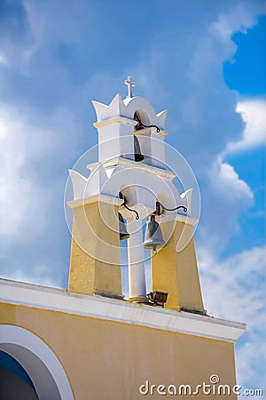 Traditional white-yellow bell tower against cloudy sky at a greek island Stock Photo