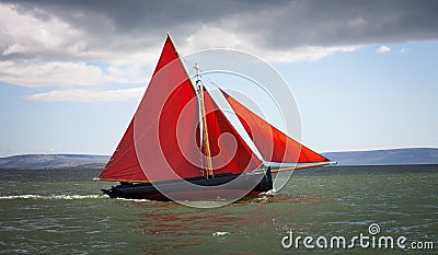Traditional wooden boat with red sail. Stock Photo