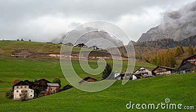 Traditional wooden cottage mountain houses in the green field in the dolomites. Housing in Italian apls. Alpine region Stock Photo