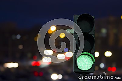 Traffic light green signal on the night on the back lights of cars. Stock Photo