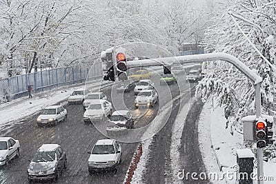 traffic light and moving cars passing fast through street on snowy day Editorial Stock Photo