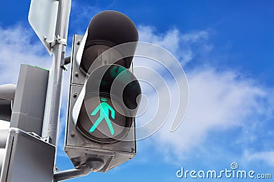 Traffic lights with the green light lit for pedestrians against blue sky background with clouds. Stock Photo