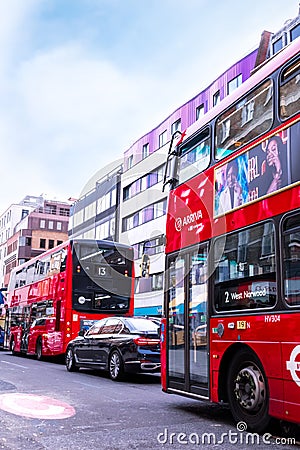 Traffic in London - two typical red buses with adverts and black mercedes, standing in traffic. Editorial Stock Photo