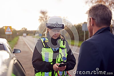 Traffic Police Officer Takes Witness Statement From Driver At Road Traffic Accident On Mobile Phone Stock Photo