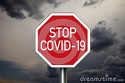 Traffic sign with dark cloudy sky with message Stop Covid 19 Stock Photo