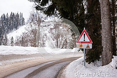 Red triangle road traffic warning sign - Other Danger. Crossroads with cross-country skis paths . Snow covered road, trees and mou Stock Photo