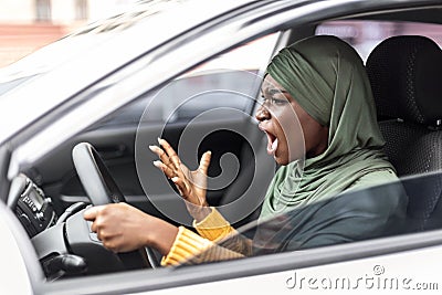 Traffic Stress. Angry black muslim female driving car and shouting at somebody Stock Photo