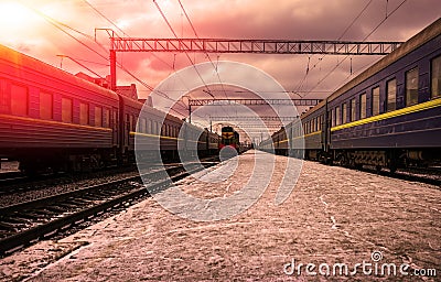 Train arrives at the station with trains at red sunset Stock Photo