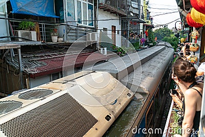 Train running on railway road with tourist watching the train from railway cafe in Hanoi, Vietnam Editorial Stock Photo