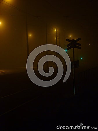 Train tracks next to a road surrounded by darkness Stock Photo