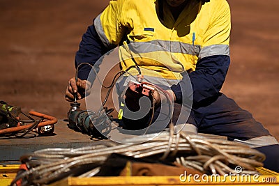 Trained competent electrician setting holding red electricity tester conducting safety testing tagging electricity power grinder Stock Photo