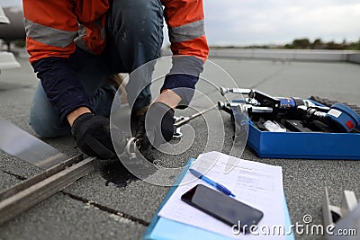 Trained safety auditor wearing safety glove inserting pin into industrial rope access certifies anchor point Stock Photo