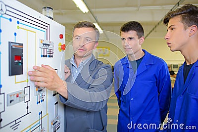 Trainee electricians looking at wiring plan Stock Photo