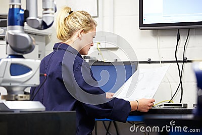 Trainee Engineer Studying Plans With CMM Arm In Foreground Stock Photo