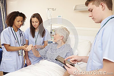 Trainee Nursing Staff By Female Patient's Bed In Hospital Stock Photo