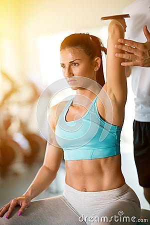 Trainer correcting woman lifting dumbbells Stock Photo