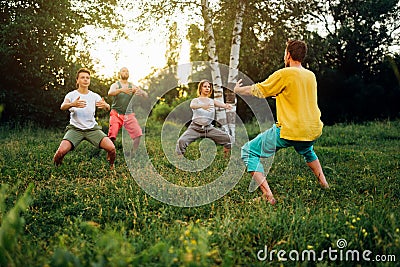 Trainer explains how to do manu stance exercise. Group learning qigong in nature. Stock Photo