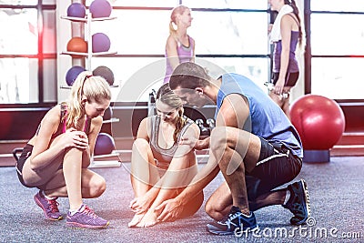 Trainer helping woman with painful ankle Stock Photo