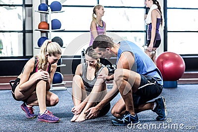 Trainer helping woman with painful ankle Stock Photo