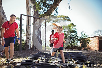 Trainer instructing kids during tyres obstacle course training Stock Photo