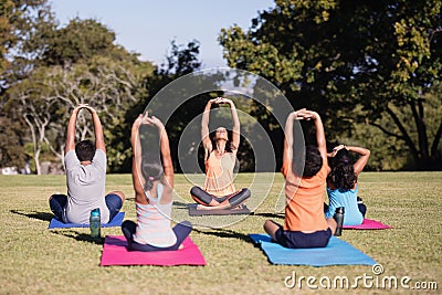 Trainer teaching children stretching while sitting on mat Stock Photo